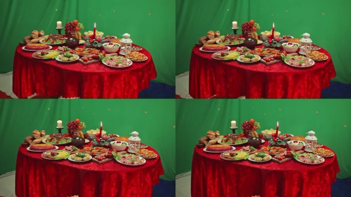 摆满食物的烛光桌和绿色背景上的食物。面包、沙拉、水果、蔬菜、肉类菜肴。鲜红色的桌布。