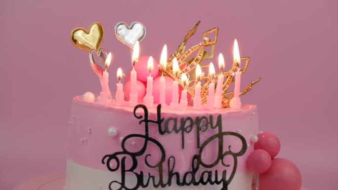 粉红色的生日蛋糕，金色的皇冠和燃烧的蜡烛