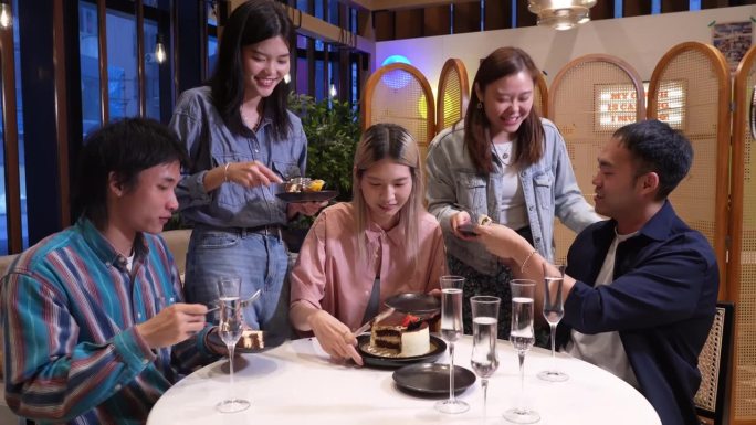 年轻的亚洲女子和她的朋友们一起在咖啡馆里吃着食物和咖啡庆祝。