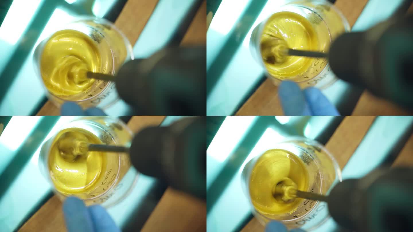 工业用搅拌器搅拌塑料杯内致密黄色物质制成的透明环氧树脂和黄色颜料粉末，形成环氧树脂黄色样品的工艺，用