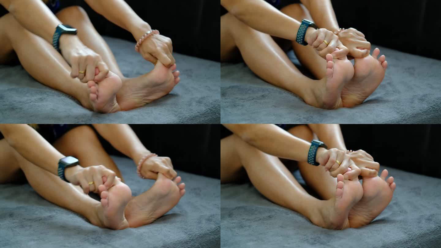 足部疼痛，亚洲女性坐在家里感觉足部疼痛，患有足部疼痛的女性用手按摩来放松脚底肌肉
