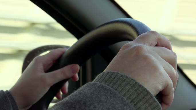 Hands Of Woman Driving Car On Highway: closeup Whe