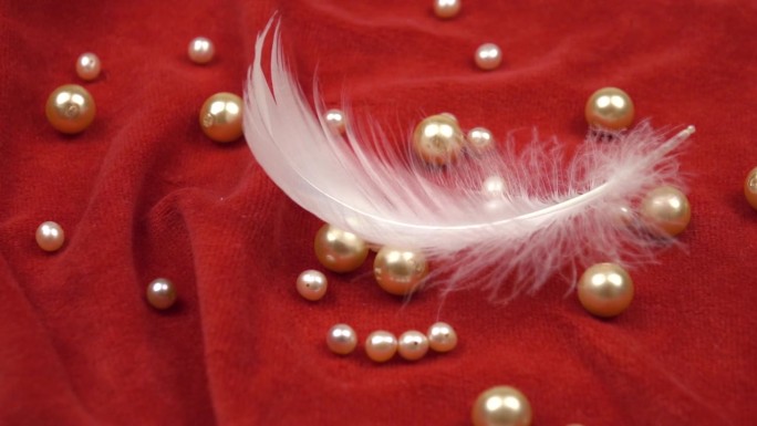 白色的天鹅羽毛和红色天鹅绒上的珍珠珠，慢动作