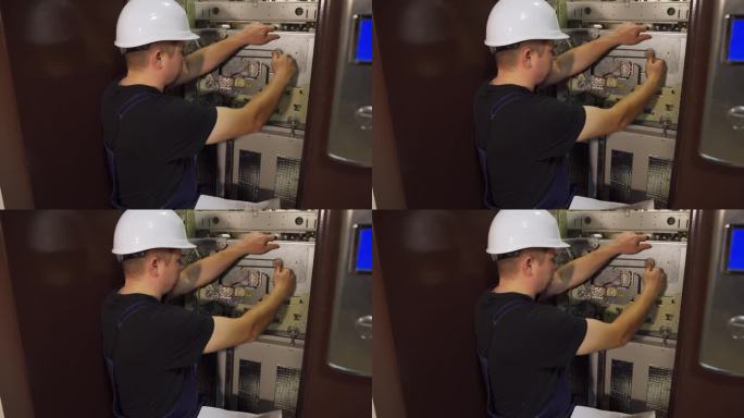 紧急停止。一位戴着白色头盔的工程师正在修理电梯，拧紧调节螺栓。按照工程要求对电梯井内的电梯设备进行维