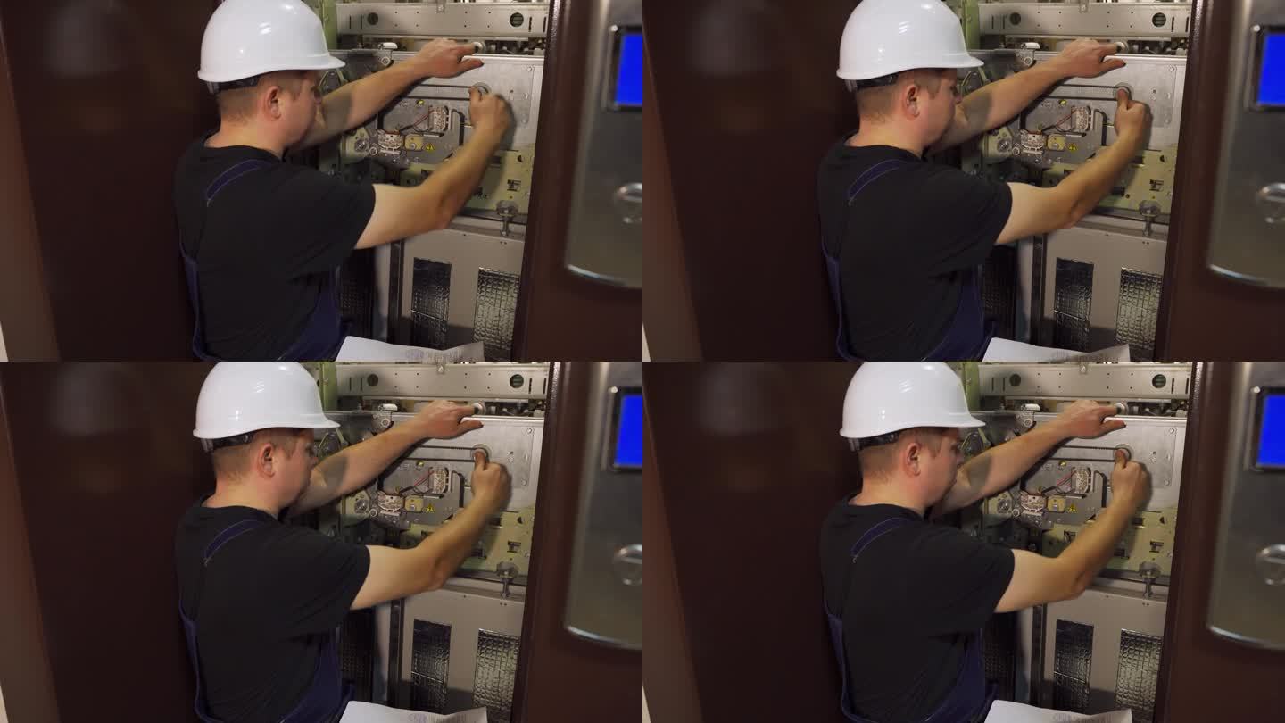紧急停止。一位戴着白色头盔的工程师正在修理电梯，拧紧调节螺栓。按照工程要求对电梯井内的电梯设备进行维