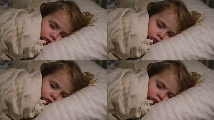 安静可爱的宝宝睡在家里的床上。熟睡的小孩。两岁的女孩安静地睡在家里的房间里。宁静的梦。可爱的脸特写。
