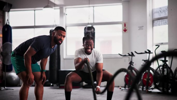 男人，私人教练和健身与战斗绳在健身房锻炼，锻炼或肌肉耐力的动机。有耐力、有氧运动或高强度训练教练的活