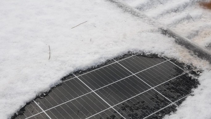 冬天用扫帚从太阳能板上清除雪和水。
