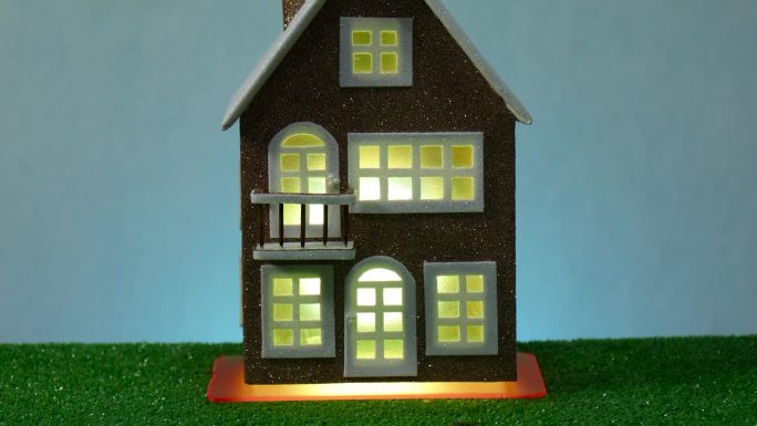 在浅蓝色的背景上，一幢棕色的房子在窗户上闪烁着黄色的光