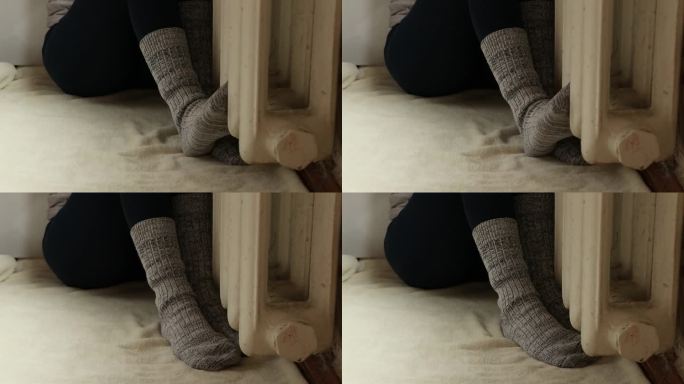 穿着袜子的脚放在公寓里的铸铁散热器上，没有暖气