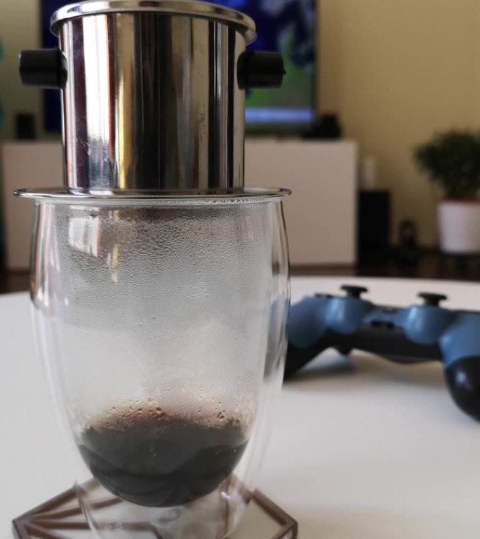 越南滴滤咖啡机在白色桌子上的垂直镜头，模糊的背景中有一个操纵杆