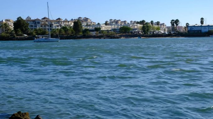 2023年8月16日，西班牙韦尔瓦的克里斯蒂娜岛:游艇在克里斯蒂娜岛开曼岬海滩前的海面上航行