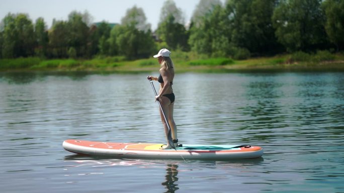 一个穿比基尼的女人在水里的桨板上