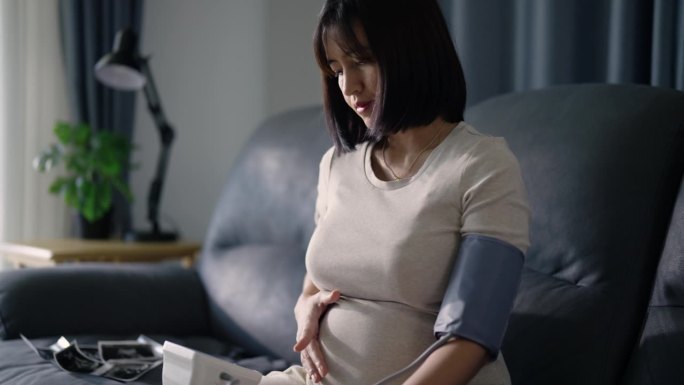 一位年轻的孕妇在家里测量自己测的血压。