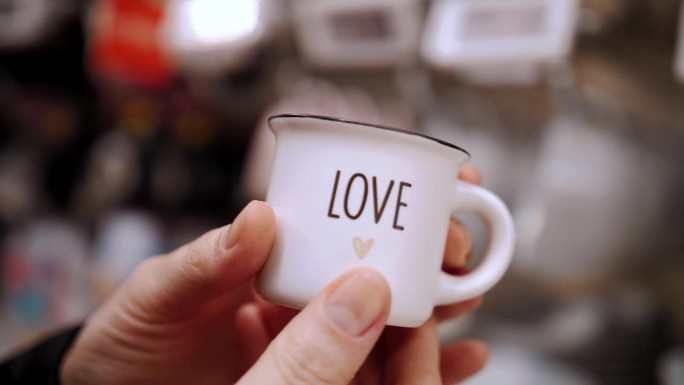 情人节。特写镜头。小小的咖啡杯，写着爱，握在手里。作为一种感情和爱的表达。爱的概念。