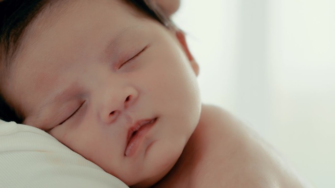 近距离接触婴儿或新生婴儿的脸婴儿感到困倦快乐的单身妈妈把小婴儿抱在肩上保护宁静的睡眠照顾健康舒适安全