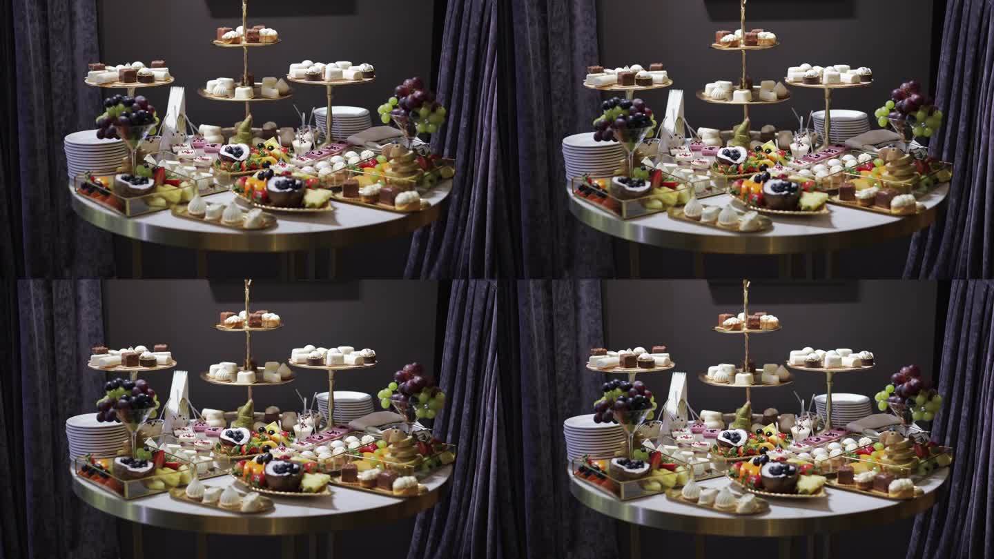 优雅的圆桌上摆放着各式各样的甜点。几种类型的糖果，包括纸杯蛋糕、糕点和水果。三层站在中间，拿着额外的
