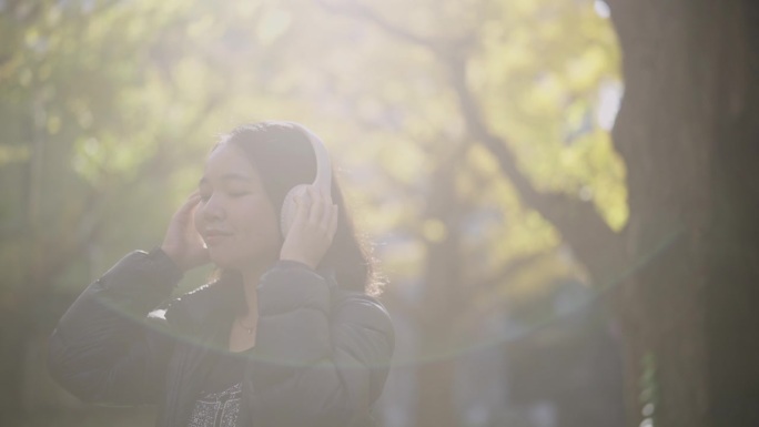 年轻的亚洲女子戴着耳机听音乐。