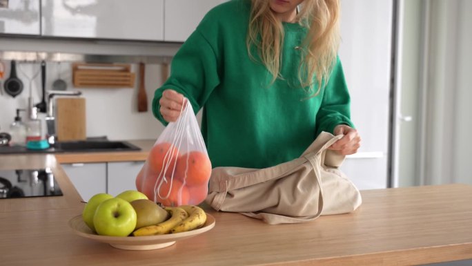 一位女士在购物时使用可重复使用的袋子。白人女性拿出袋子里的水果。可持续购物理念。