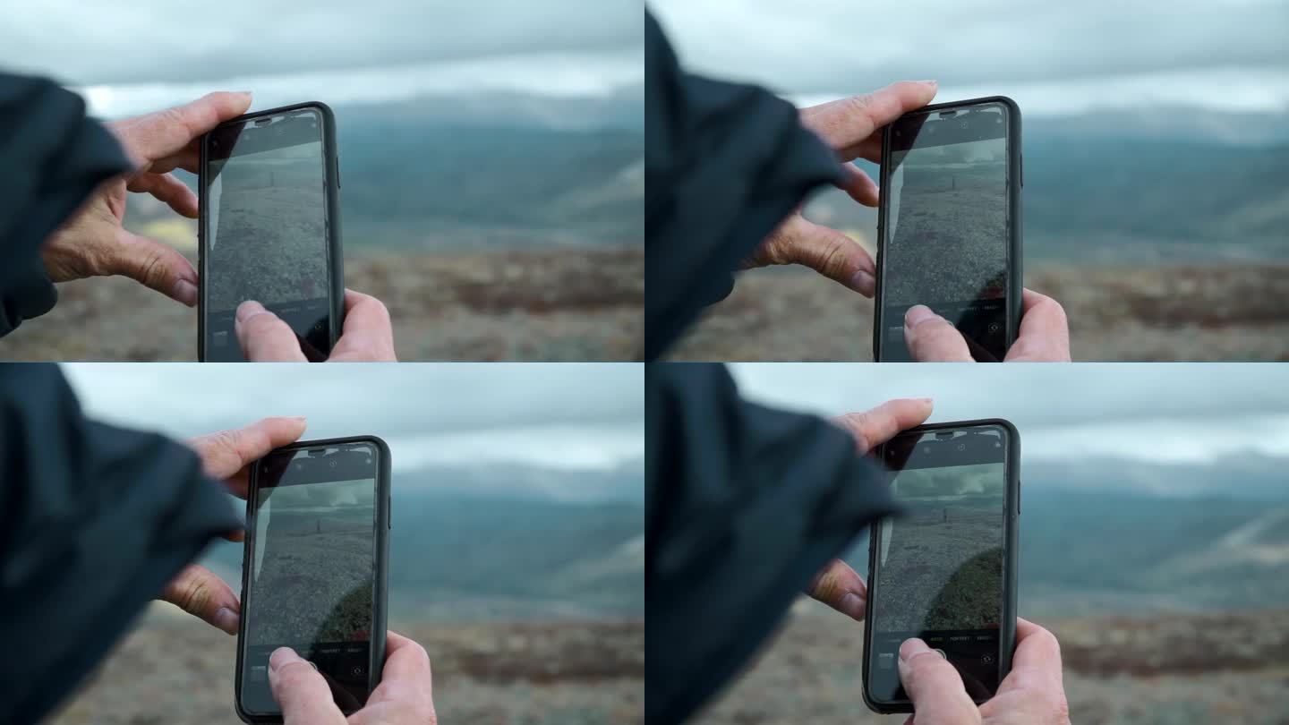 人与人拍摄山景的特写。夹。手机屏幕在人的手里。
