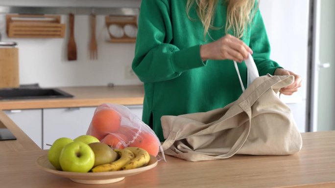 可持续的生活方式，女人用手提袋购物。女性从家里的手提袋里拿出可重复使用的水果袋。