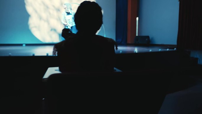 在黑暗的房间里，一个人在大屏幕上看电影的剪影。