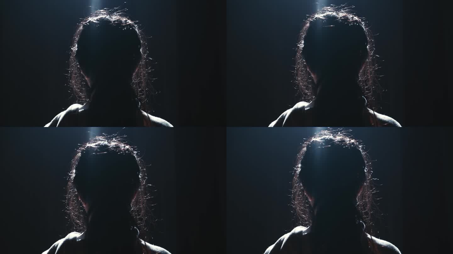 一个人的剪影与背光的头发在黑暗的背景。