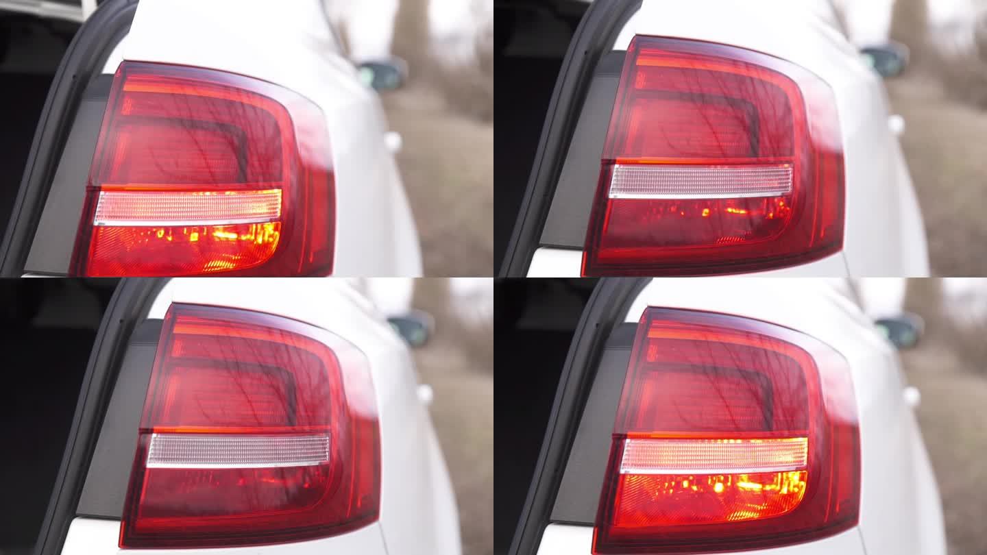 一辆白色汽车前灯的特写，转向灯在闪烁。汽车报警器响了。安全的信号。