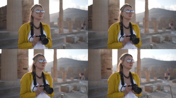 女游客在游览雅典卫城时拿着相机。