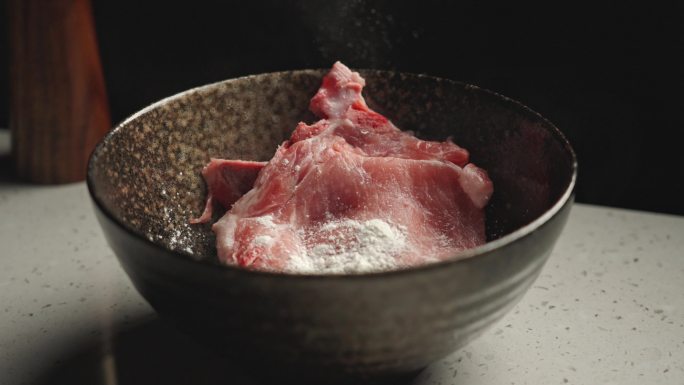 在碗中的猪肉上加入淀粉腌制