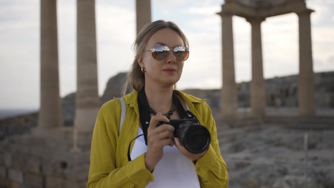 女游客在游览雅典卫城时拿着相机。