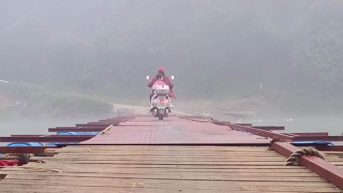 家长摩托车接送小学生晨雾浮桥骑摩托车过桥