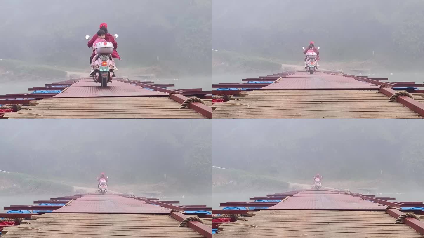 家长摩托车接送小学生晨雾浮桥骑摩托车过桥