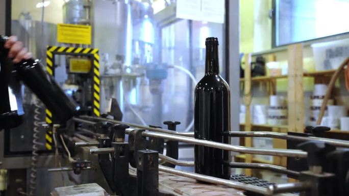 员工将红酒杯放在传送带上贴标签，然后再装盒出售，酿酒厂自动装瓶传送带，高品质葡萄酒生产线