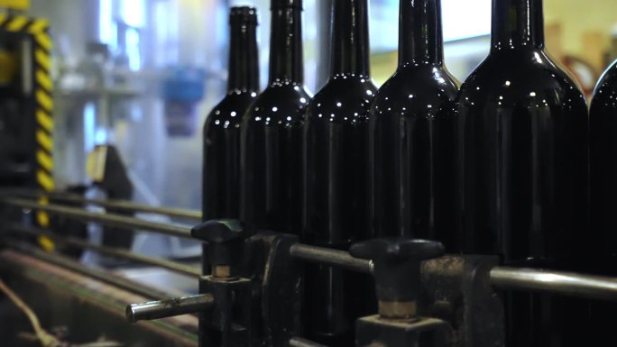 移动红酒玻璃瓶传送带，工人将红酒放在传送带上贴标签，然后进行分库，红酒生产线和自动装瓶传送带