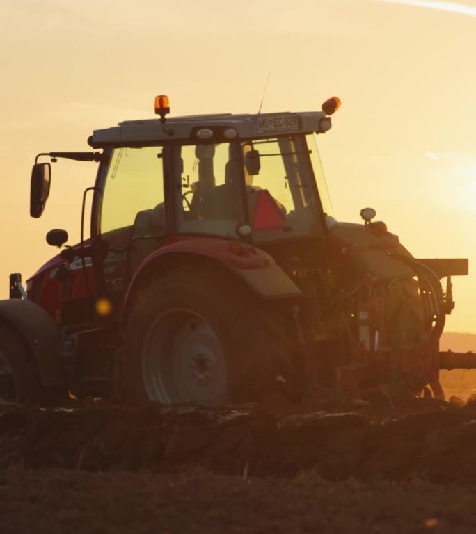 日落时分，男农民在拖拉机上对着天空耕作有机农场