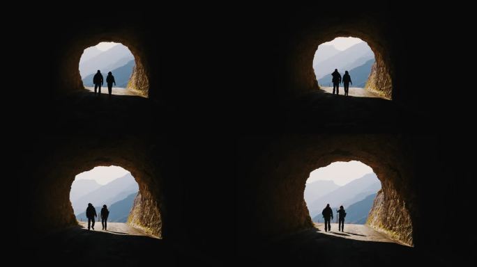 SLO MO入光:徒步旅行者穿过山隧道的剪影