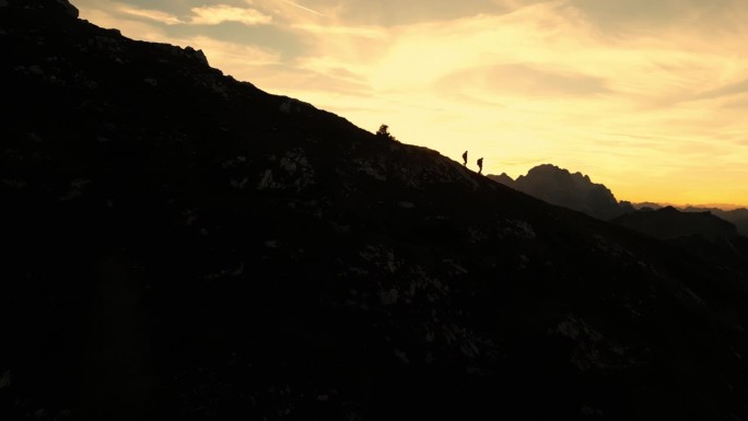 空中黄昏下降:两个徒步旅行者在山脊上下降的剪影