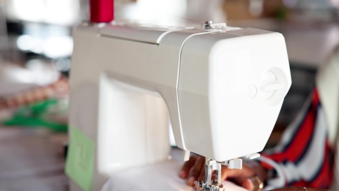 手工，缝纫机和布料在工作室制造服装，小型企业或生产。时装裁缝或电子商务，图案或创意车间的人员，手指和