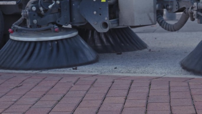 扫地车用旋转刷清洁人行道路面，动作缓慢