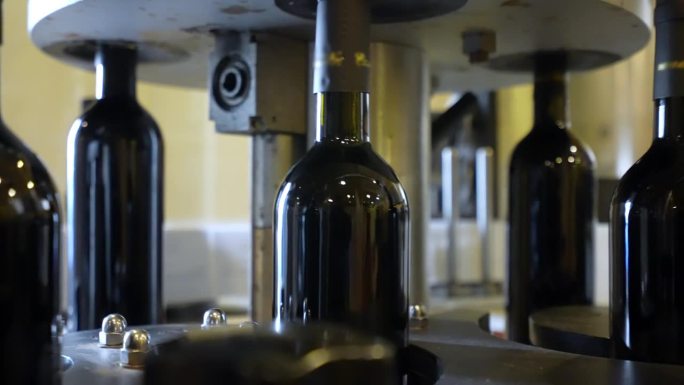 红酒瓶在移动传送带上，在配送前用软木塞封瓶并贴标签。自动装瓶输送机，红葡萄酒酒瓶制备概念