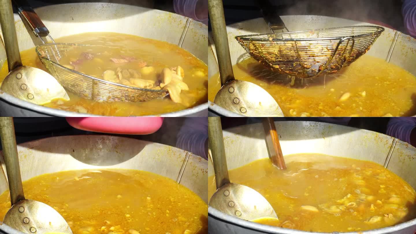一个索托破损或牛肉索托摊贩用手搅拌装满内脏的索托肉汤的大锅。