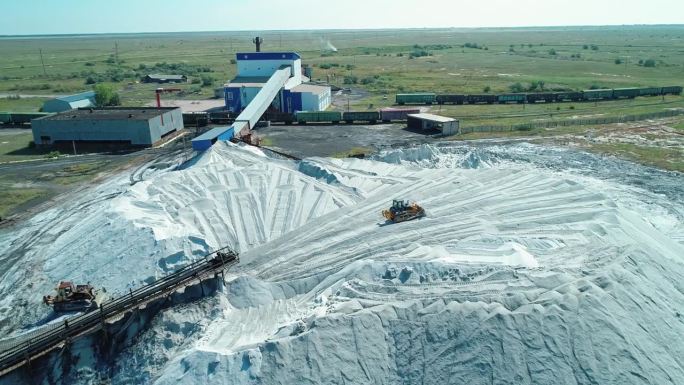 俄罗斯阿尔泰地区盐厂大堆盐的天线。跟踪器在桩上行驶。重型工业设备