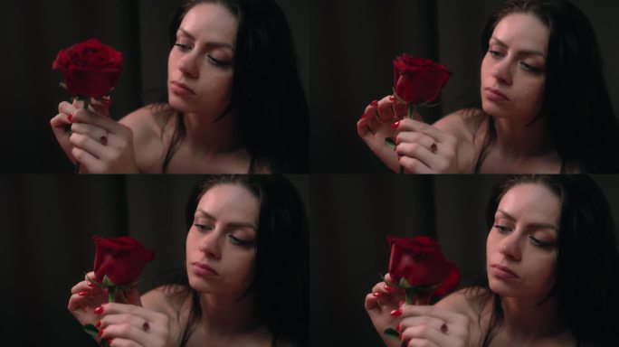 悲伤的单身女人在浪漫的假期。看着一朵玫瑰，摘着花瓣玩爱我爱我找不到爱
