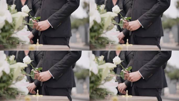 手，玫瑰和一个人在墓地的葬礼上，在追悼会上哀悼失去的亲人。死亡，鲜花和一个穿着西装的成年人，在一个墓