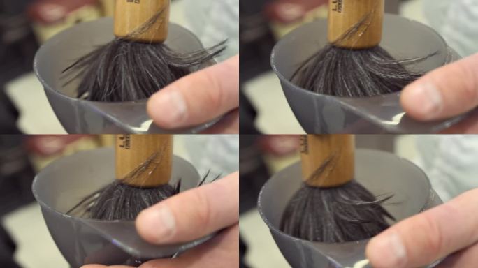 理发师的手把剃须刷浸在一杯肥皂和泡沫里。特写镜头。