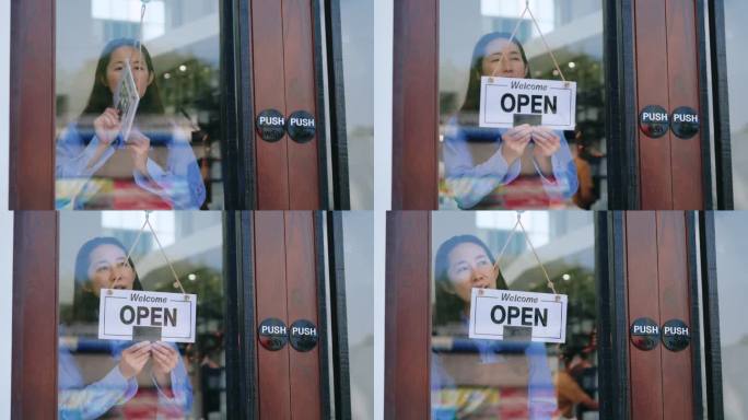 亚洲老板微笑在玻璃门后面，打开标志-欢迎顾客光临