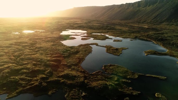 这是一架无人机在神奇的时刻拍摄的迷人的冰岛自然风光的航拍照片，这张照片捕捉到了一片非常广阔的草地，上