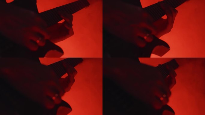 一个吉他手在黑暗的舞台上用电吉他演奏缓慢旋律的特写镜头，舞台上有红灯。演奏摇滚歌曲的音乐家