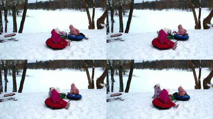 小孩子三胞胎姐妹在冬天骑在一个充气奶酪蛋糕与低雪坡